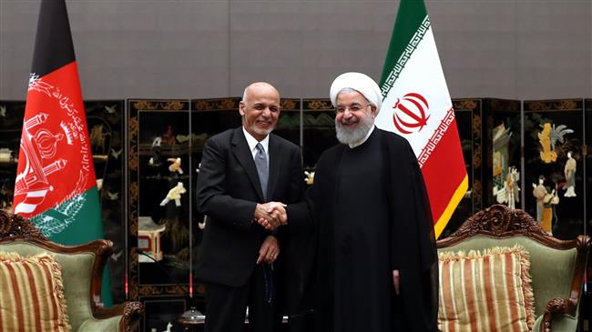 Iranian President Hassan Rouhani (R) shakes hands with his Afghan counterpart Ashraf Ghani on the sidelines of a summit of the Shanghai Cooperation Organization in the Chinese port city of Qingdao on June 9, 2018. (Photo by president.ir)