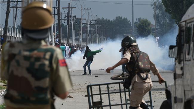 Indian police and paramilitary troopers stand guard as Kashmiri youths protest during clashes in Srinagar, Kashmir, June 16, 2018. (Photo by AFP)