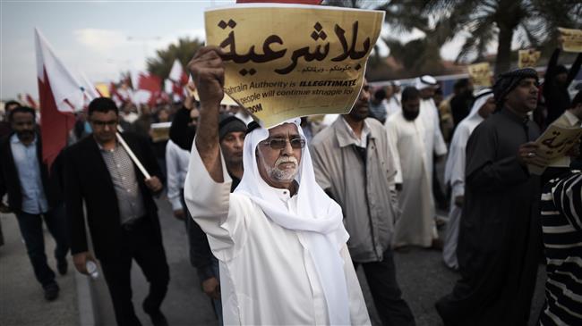 The file photo shows a Bahraini man holding up a placard reading, "Your government and your parliament are without legitimacy" during an anti-regime protest in the village of Jannusan, west of the Manama. (Photo by AFP)