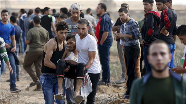 Palestinians carry a wounded protester who was shot by Israeli troops during clashes near the border