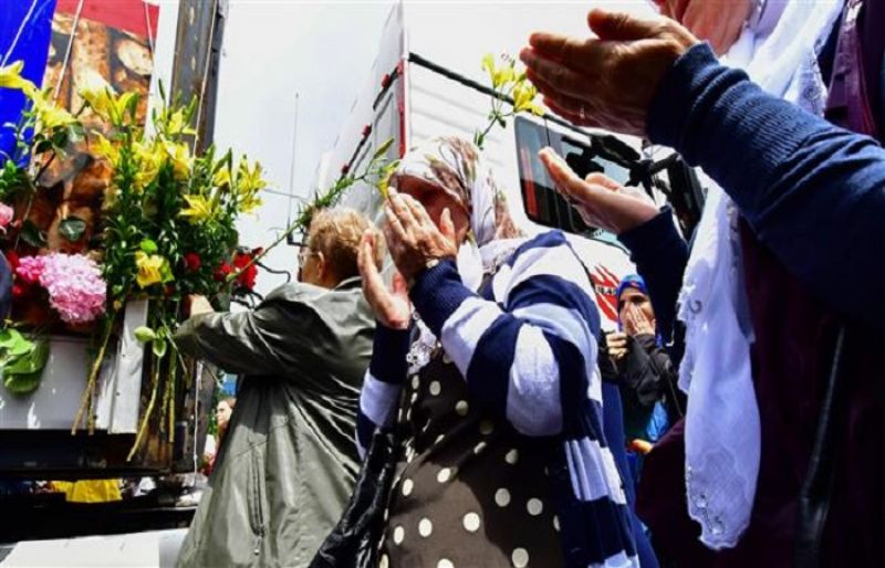 Bosnian Muslims, citizens of Sarajevo, pray near a truck, carrying the remains of 35 newly identified victims of Srebrenica massacre, while it makes a short stop in Sarajevo city center, on July 9, 2018. (AFP)