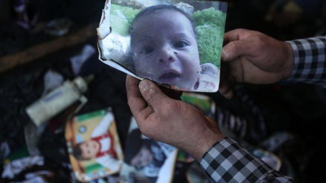 A man holds a picture of Palestinian toddler Ali Dawabsheh, who died when the family home was set on fire in the occupied West Bank village of Duma on July 31, 2015. (Photo by AFP)