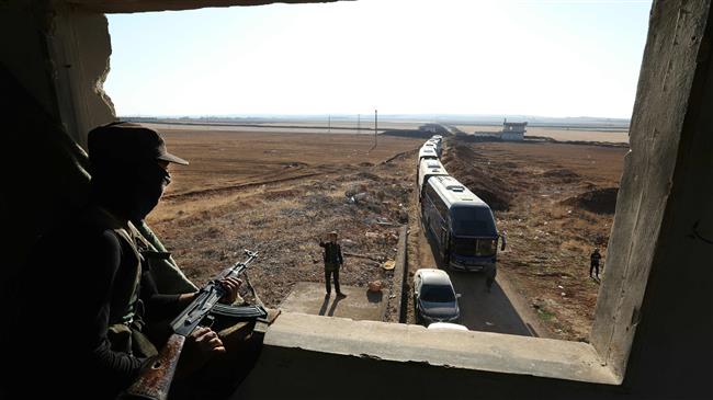 A militant watches as a convoy of buses gets ready to enter the towns of Foua and Kefraya to evacuate their residents on July 18, 2018. (Photo by AFP)