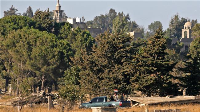 A picture taken on July 26, 2018, near the Ein Zivan settlement in the Israeli-occupied Golan Heights, shows members of the Syrian security forces carrying a national flag across the border as government forces retake their positions from the militants. (AFP photo)