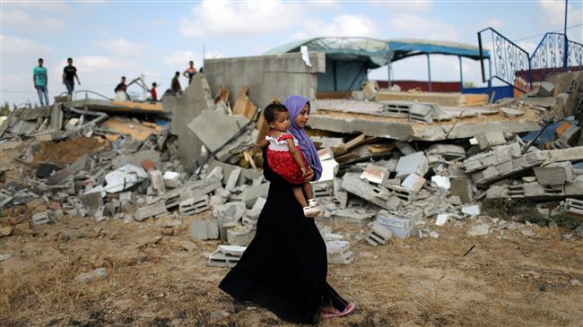A Palestinian woman carries a girl as she walks past the site of an Israeli airstrike, in the city of Khan Yunis in the southern Gaza Strip on August 9, 2018. (Photo by Reuters)
