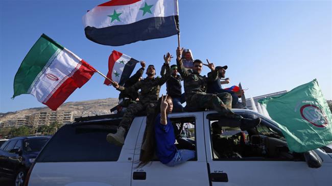 Troops and ordinary citizens in Damascus wave Syrian and Iranian flags as they chant slogans against the US following airstrikes in the capital, April 14, 2018.