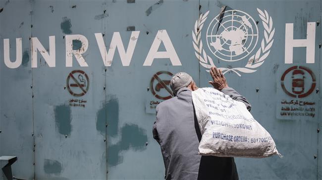 A Palestinian man stands in front of the emblem of the UN Relief and Works Agency for Palestine Refugees (UNRWA) outside the agency’s offices in Gaza on July 31, 2018. (AFP Photo)