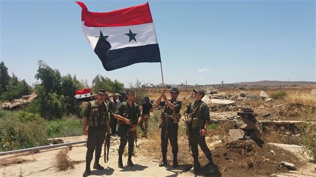 A handout picture released by the official Syrian Arab News Agency (SANA) on July 26, 2018 shows Syrian army soldiers carrying the national flag in the village of Hamidiya in the southern province of Quneitra. (Via AFP)