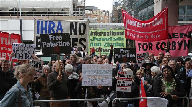Demonstrators hold placards as they protest outside the headquarters of Britain
