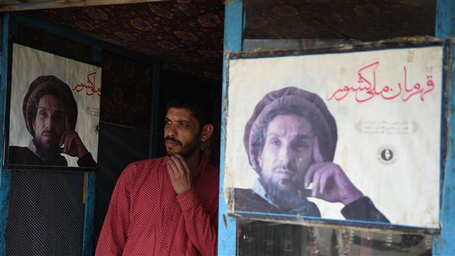 The file photo shows an Afghan shopkeeper standing next to the posters of Ahmad Shah Massoud, the largely revered leader also known as the Lion of Panjshir, in Kabul on May 6, 2018. (Photo by AFP)