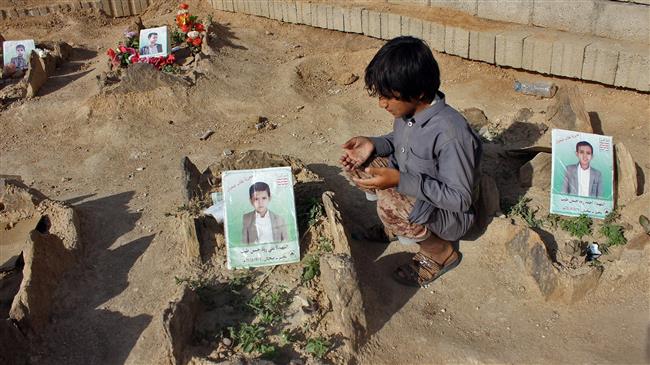 A Yemeni child recites a prayer by the graves of schoolboys who were killed while on a bus that was hit by a Saudi-led coalition airstrike in August. (Photo by AFP)
