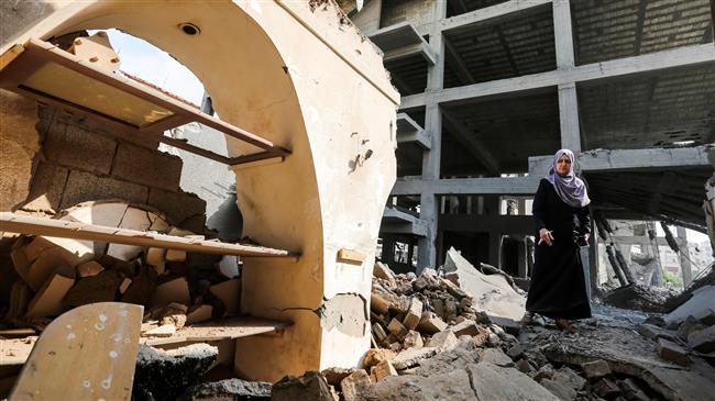 A Palestinian woman walks through rubble in the damaged Arts and Crafts Village, adjacent to a building that was hit by Israeli airstrikes the day before, in Gaza City on July 15, 2018. (By AFP)