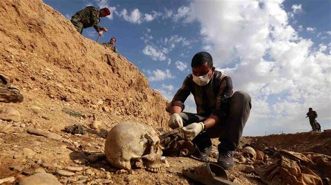 In this file picture, an Iraqi man inspects a mass grave near the town of Sinjar, situated over 400 kilometers northwest of the capital Baghdad. (Photo by AFP)