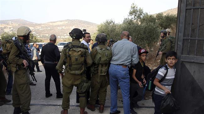 School children and Israeli soldiers gather at the main entrance of a Palestinian school that has been ordered by Israel to be shut down, in the town of Sawiyah, south of Nablus, in the occupied West Bank on October 15, 2018. (Photo by AFP)