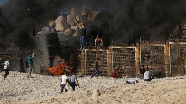 Palestinian protesters climb a fence separating them from Israeli security forces during demonstration on the beach near the maritime border with the Israeli-occupied territories, in the northern Gaza Strip, on October 15, 2018. (Photo by AFP)