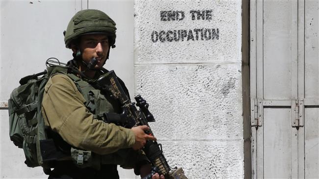 The file photo shows an Israeli soldier standing guard during a planned tour by settlers in the city of al-Khalil (Hebron) on September 25, 2018. (Photo by AFP)