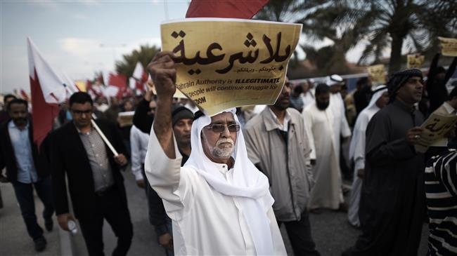 The file photo, taken on December 26, 2014, shows a Bahraini man holding up a placard reading in Arabic, "Your government and your parliament are without legitimacy," during an anti-government protest in the village of Jannusan, west of the capital Manama. (Photo by AFP)