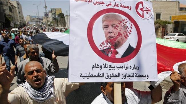 Palestinian demonstrators hold signs bearing pictures condemning US President Donald Trump.