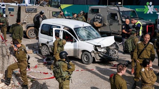 This picture taken on November 26, 2018 shows Israeli soldiers standing around a damaged car at the scene of an attack where a Palestinian man allegedly rammed a vehicle into three Israeli soldiers south of the occupied West Bank city of Bethlehem on November 26, 2018. (Photo by AFP)