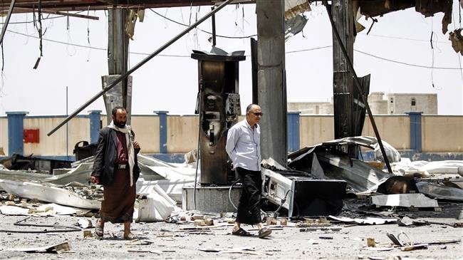 Yemeni men walk through the rubble and debris of a destroyed petrol station that was hit by a Saudi airstrike in the capital Sana’a on May 27, 2018. (By AFP)