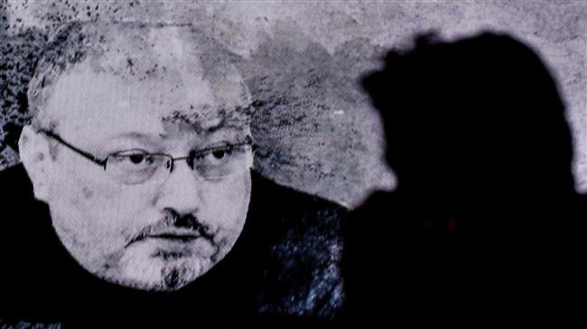 A man passes in front of a screen showing Jamal Khashoggi during a commemoration event held by Khashoggi