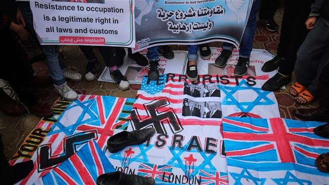 Palestinians step on flags and hold banners during a demonstration in the town of Rafah in the southern Gaza Strip on December 6, 2018. (Photo by AFP)