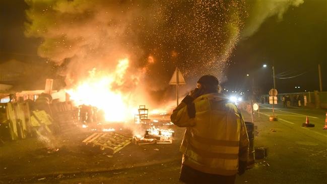 A yellow vest protestor watches as barricades burn while demonstrators block access to an oil depot in Le Mans, northwestern France, on December 11, 2018. (Photo by AFP)