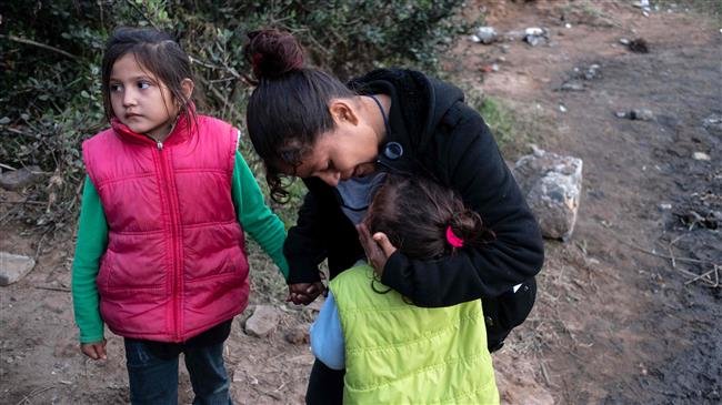 A Central American migrant travelling in a caravan, comforts her daughter as her group hesitates before attempting to cross the Mexico-US border fence to San Diego California, on December 12, 2018. (AFP photo)