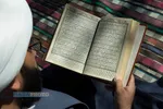 در ایوان منزل مشغول مطالعه قرآن است